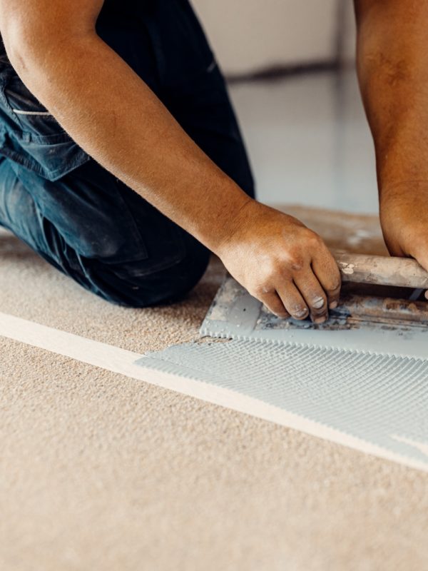 A construction worker apply grey epoxy resin in an industrial hall